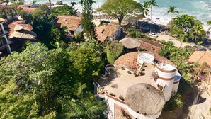 Ein Küstenresort mit strohgedeckten Gebäuden, Palmen und einem Strand.