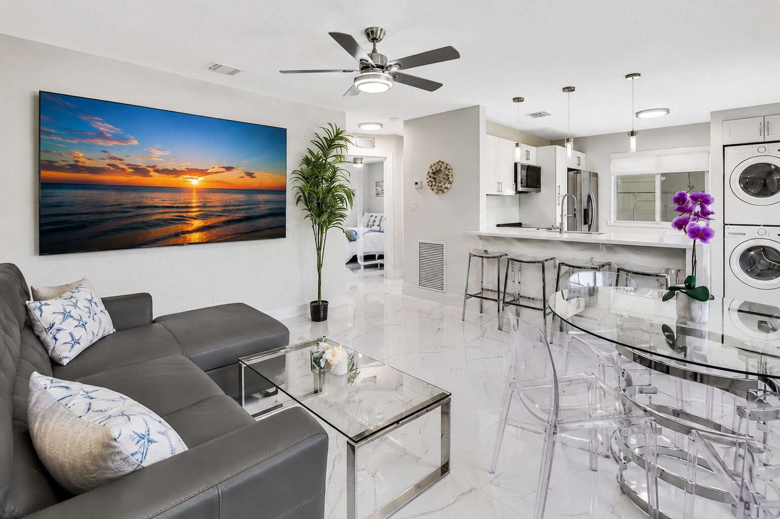 A modern living room with a sofa, coffee table, and a large painting of a sunset.