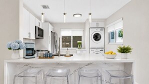 A modern kitchen with white cabinetry, a built-in washing machine, a coffee maker, and a marble countertop. - 2BR Hot Tub Oasis - 2 Mi FLL, 4 Mi Beach, Sleeps 6 (Dania Beach)