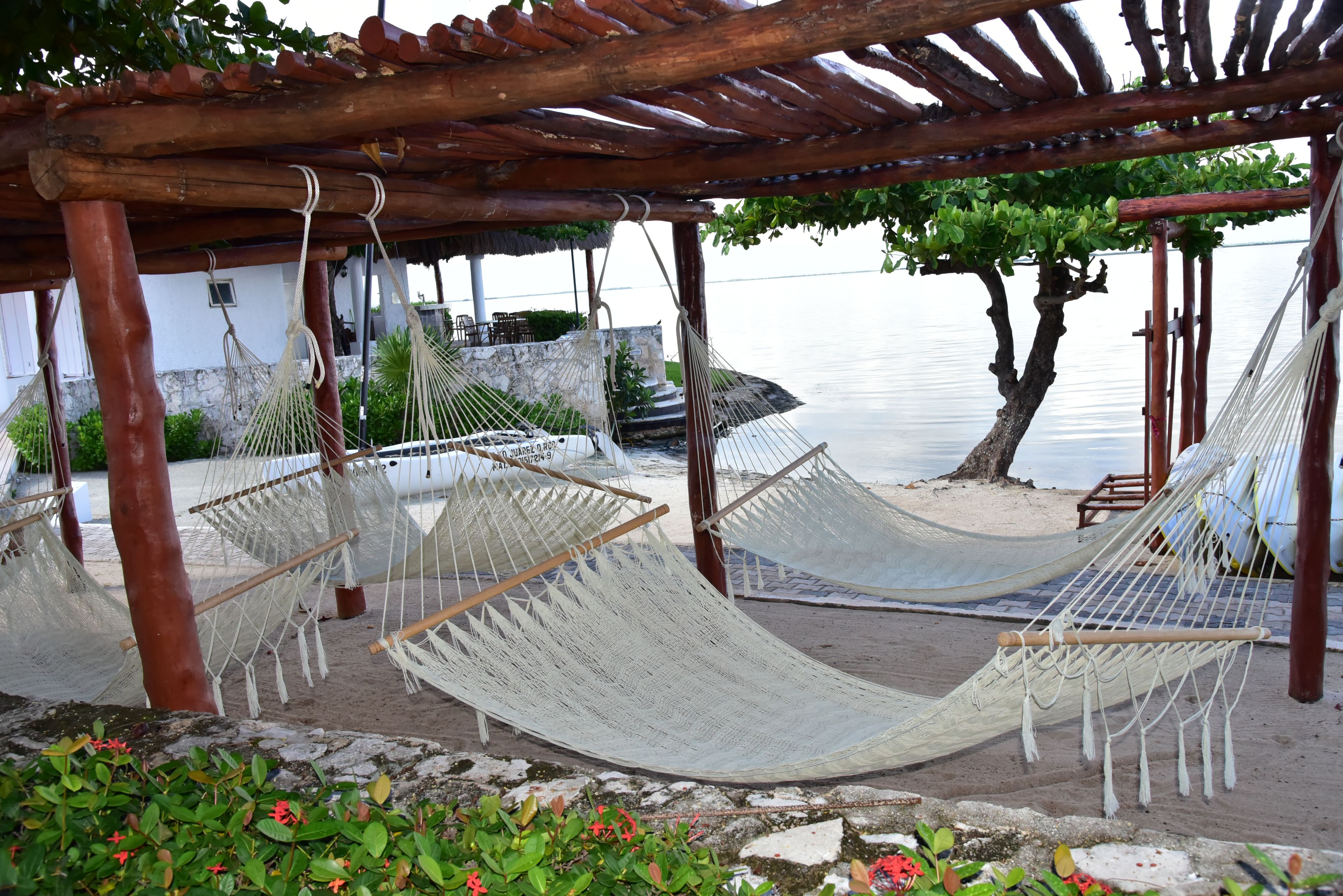A hammock area with a pergola overhead, a stone pathway, and a view of the water.