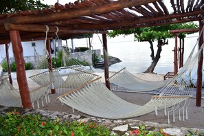 Un'area relax con amaca, un pergolato sopra e vista sull'acqua.