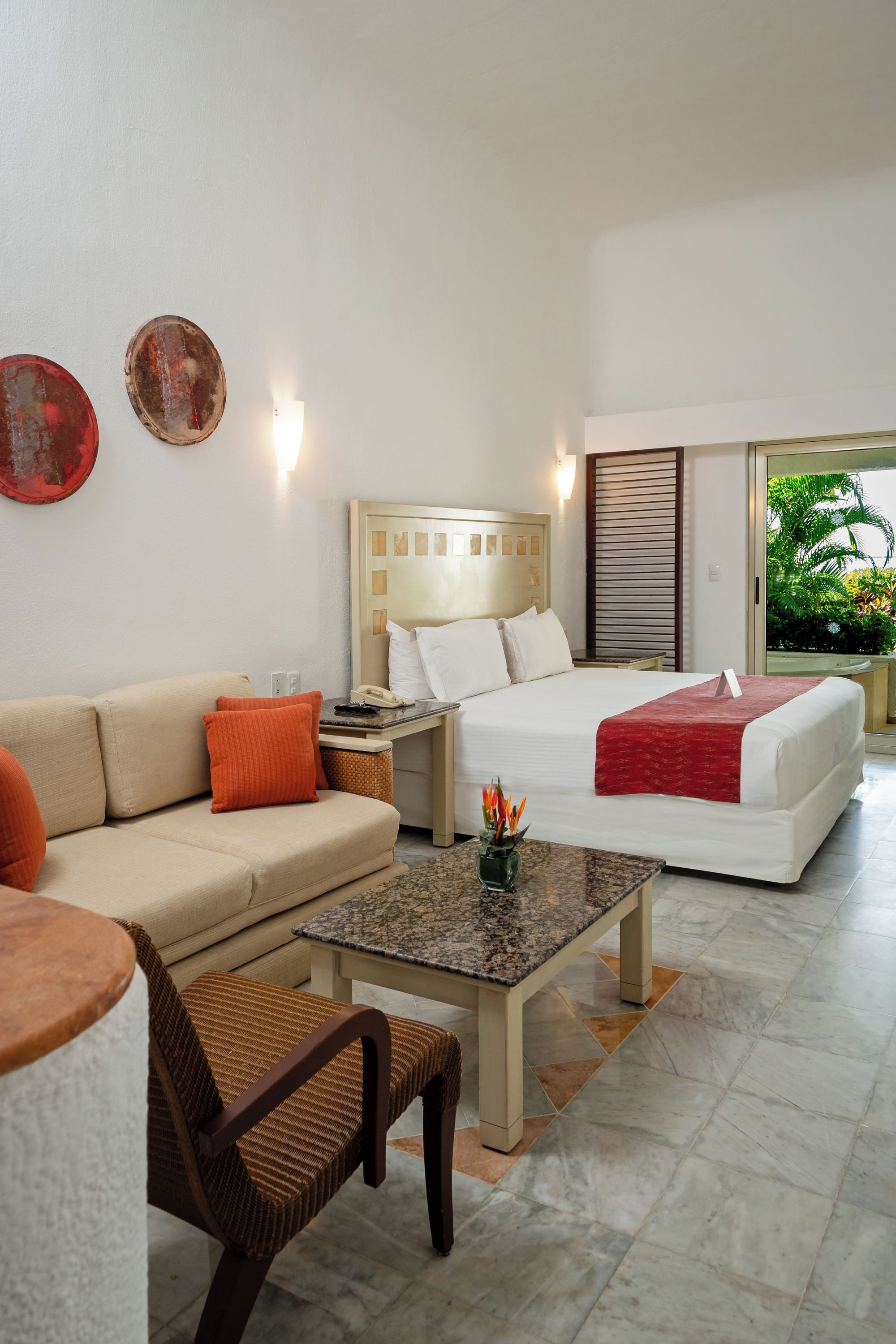 A hotel room with a bed, a sofa, a coffee table, a chair, and a nightstand.