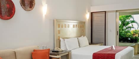 Una habitación de hotel con cama, sofá, mesa de centro, silla y mesita de noche.