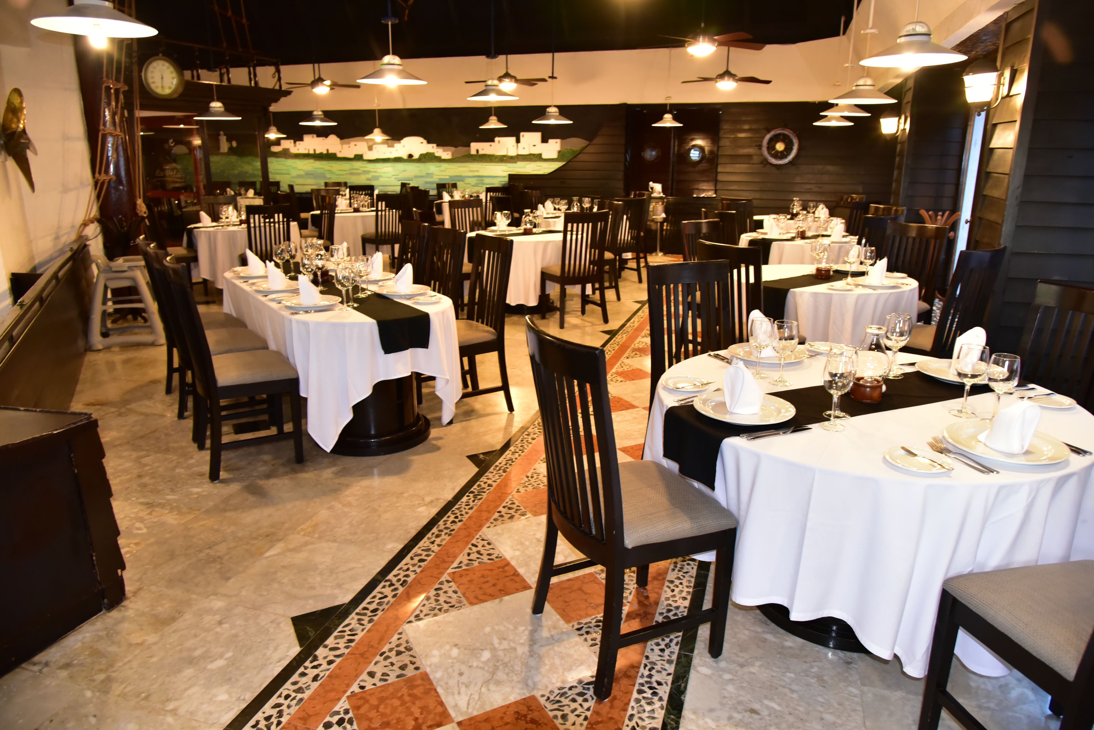 A restaurant with multiple tables set for dining, featuring a mix of chairs and benches.