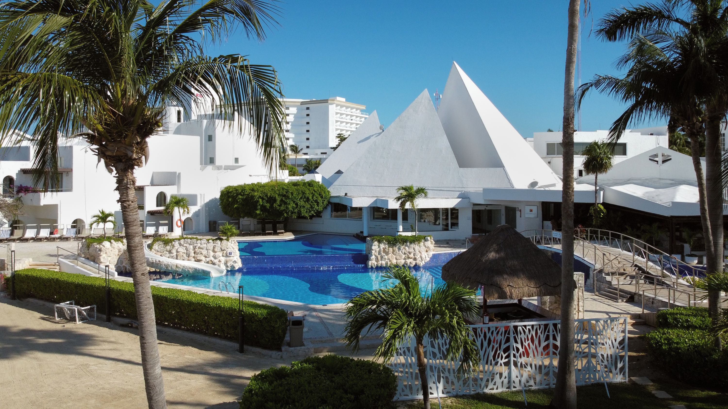 A resort with a swimming pool, palm trees, and modern architecture.