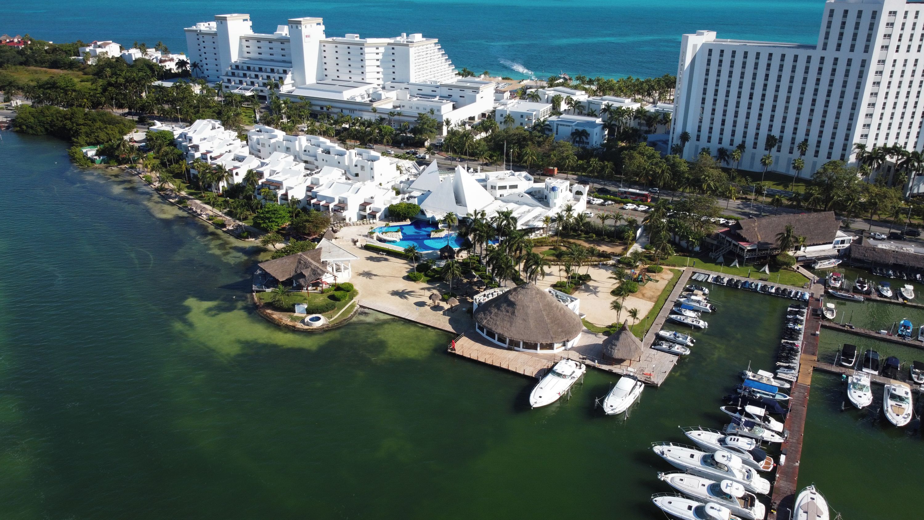 An aerial view of a coastal resort with multiple buildings, a marina, and a swimming pool.