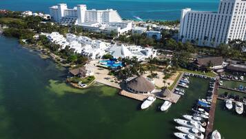 An aerial view of a coastal resort with multiple buildings, a marina, and a swimming pool.