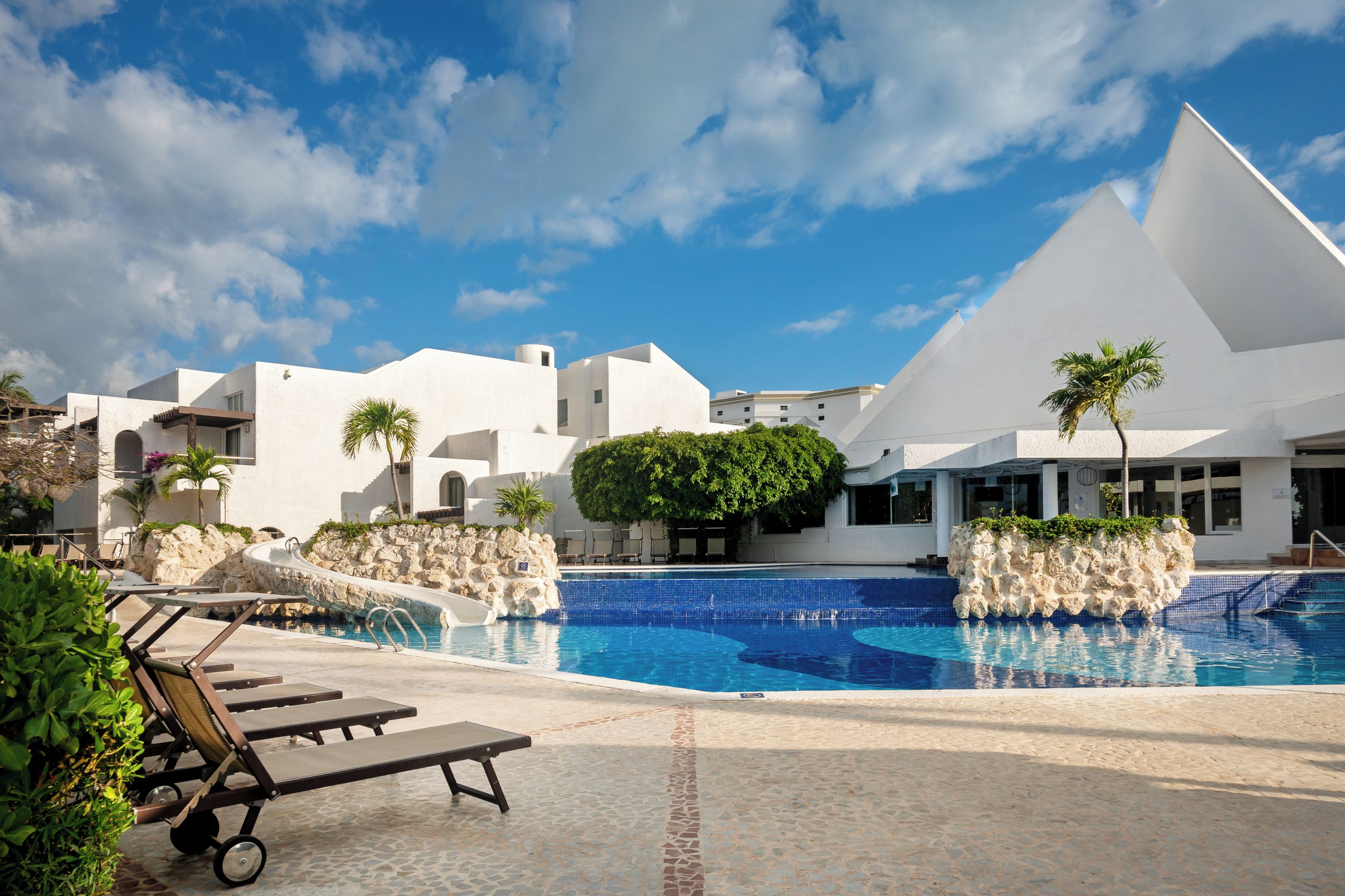 A pool area with lounge chairs and a clear blue sky.