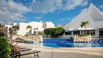 A pool area with lounge chairs and a clear blue sky.
