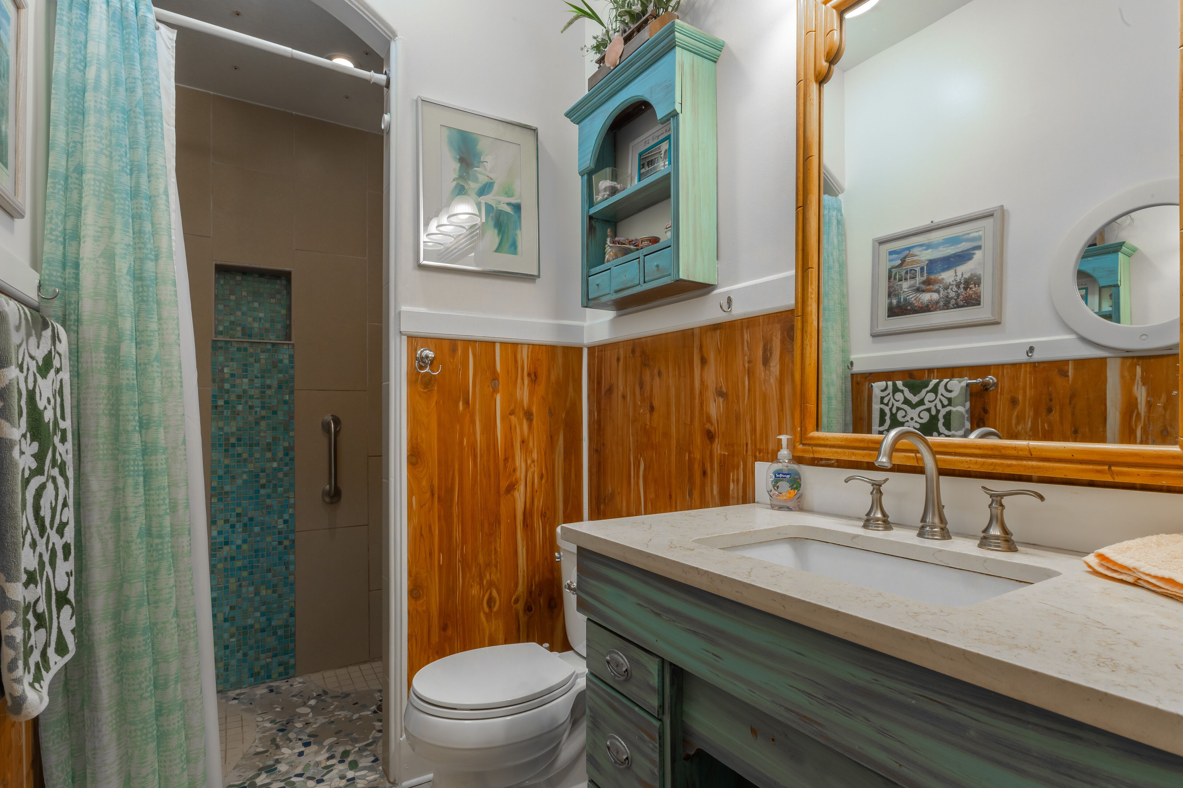 A bathroom with a wooden vanity, a sink with a mirror, and a toilet.