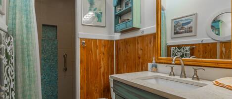 A bathroom with a wooden vanity, a sink with a mirror, and a toilet.