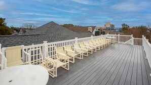 A wooden deck with white railings and beige chairs.