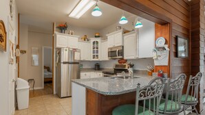 A kitchen with white cabinets, a granite countertop, and a central island with bar stools.