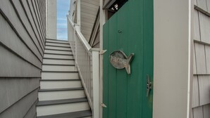 A staircase leading to a green door with a 'WELCOME' sign.