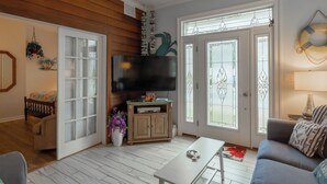 A living room with a flat-screen TV, a sofa, a coffee table, and a dining table.