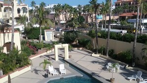 Un área de piscina con sillones de descanso y palmeras.