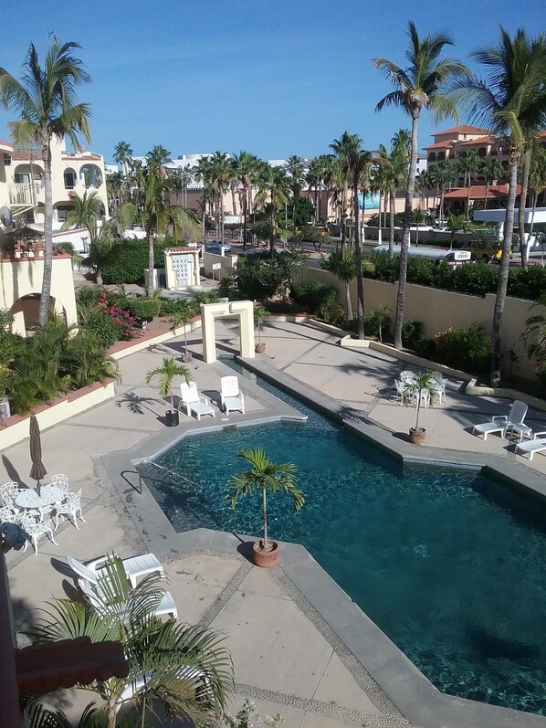 A pool area with lounge chairs and palm trees.