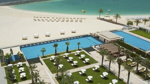 Un resort con una grande piscina, spiaggia e area relax con ombrelloni.