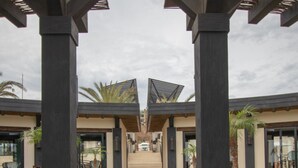 Een pad dat leidt naar een gebouw met een symmetrisch ontwerp, met een centrale looppad aan weerszijden van twee kolommen en een trap op de achtergrond.