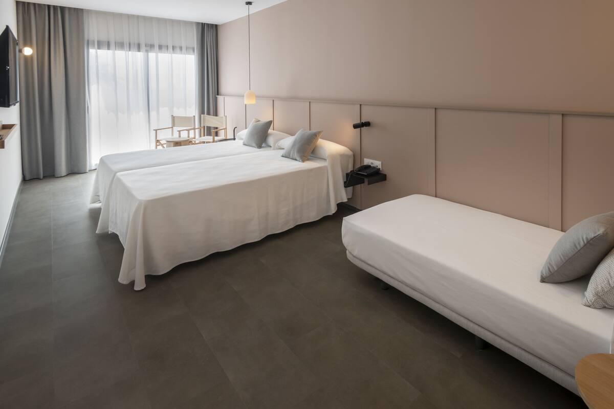 Een hotelkamer met twee bedden, een bureau en een stoel.