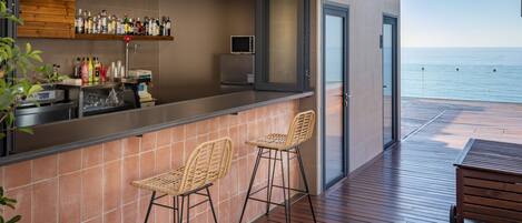 Una zona de bar con mostrador, dos taburetes de mimbre y un televisor.