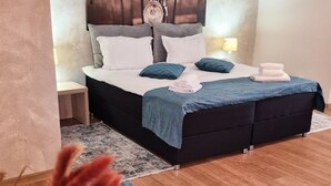 Un dormitorio con cama, mesitas de noche, una obra de arte en la pared y suelo de madera.