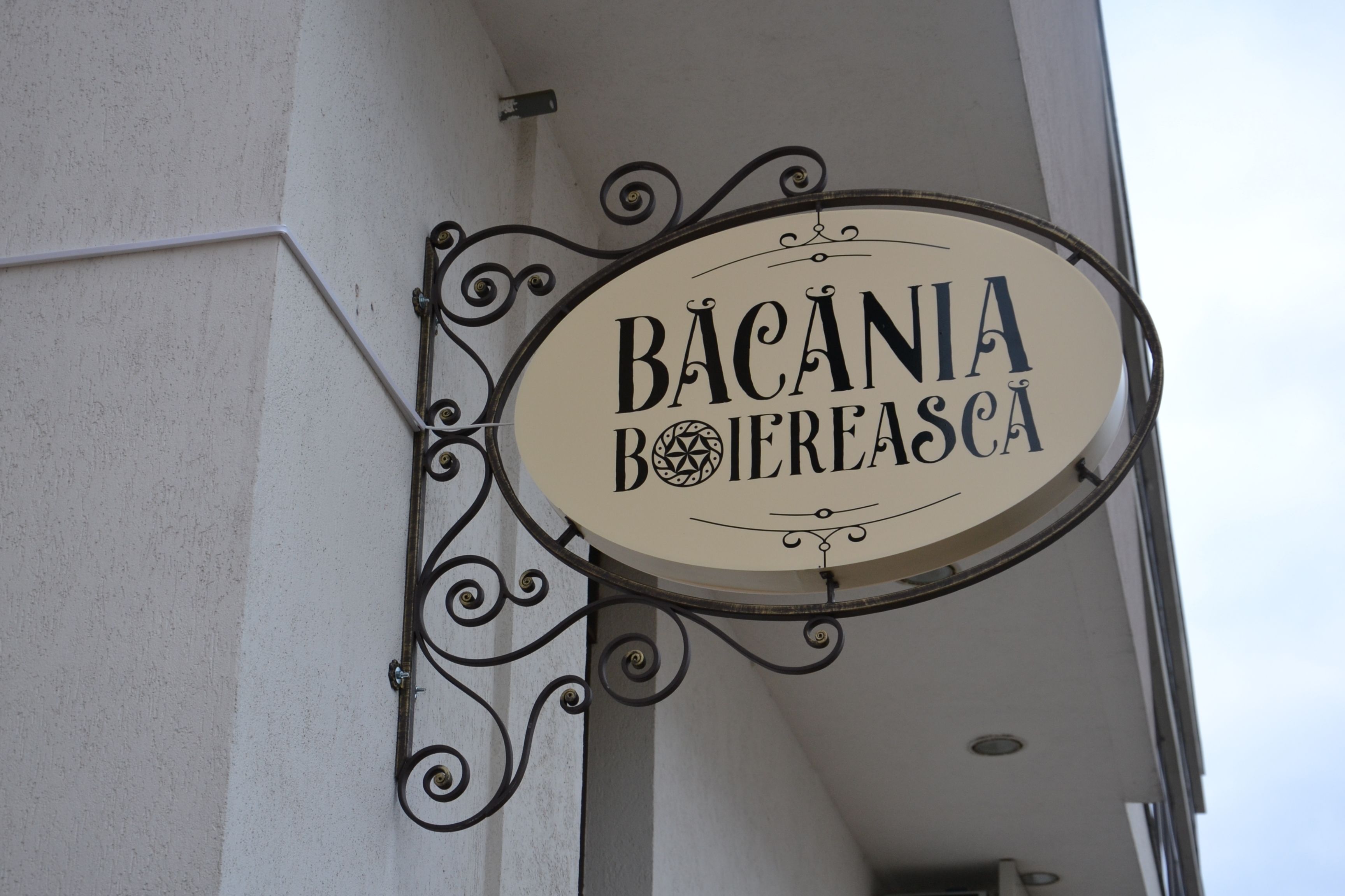 Een bord met de tekst 'BACANIA BOJEREASCA' aan een gebouw bevestigd.