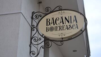 Een bord met de tekst 'BACANIA BOJEREASCA' aan een gebouw bevestigd.