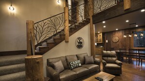 Una sala acogedora con escalera de madera, sofá de cuero y una mesa de comedor.
