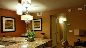 A kitchen with granite countertops, a central island with a plant, and a dining area with a patterned sofa.