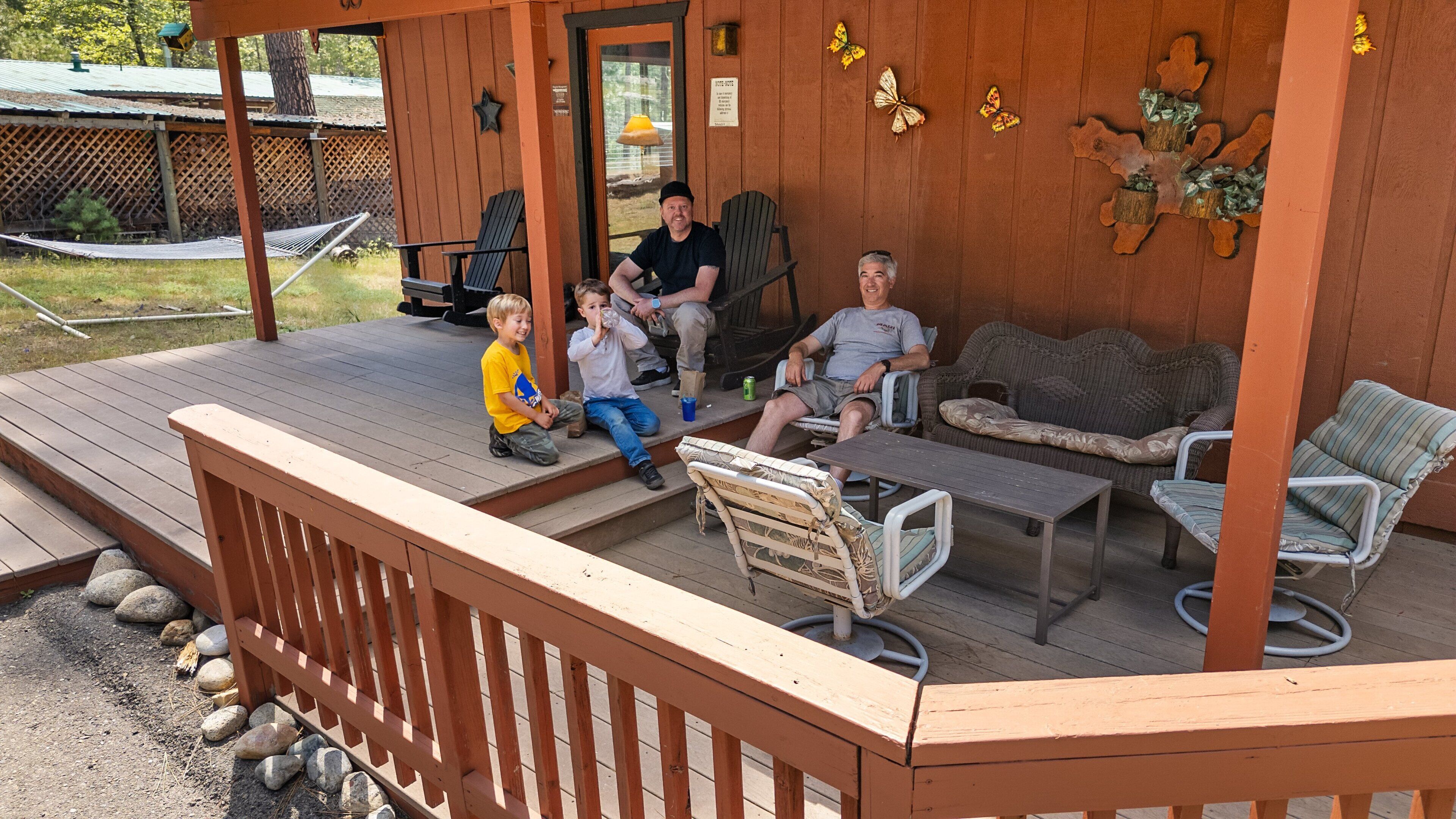 A wooden deck with outdoor seating, including a sofa, chairs, and a small table.