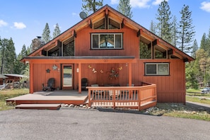 Surrounded by tall pine trees, this lodge offers a two-story retreat with a spacious front porch and balcony.