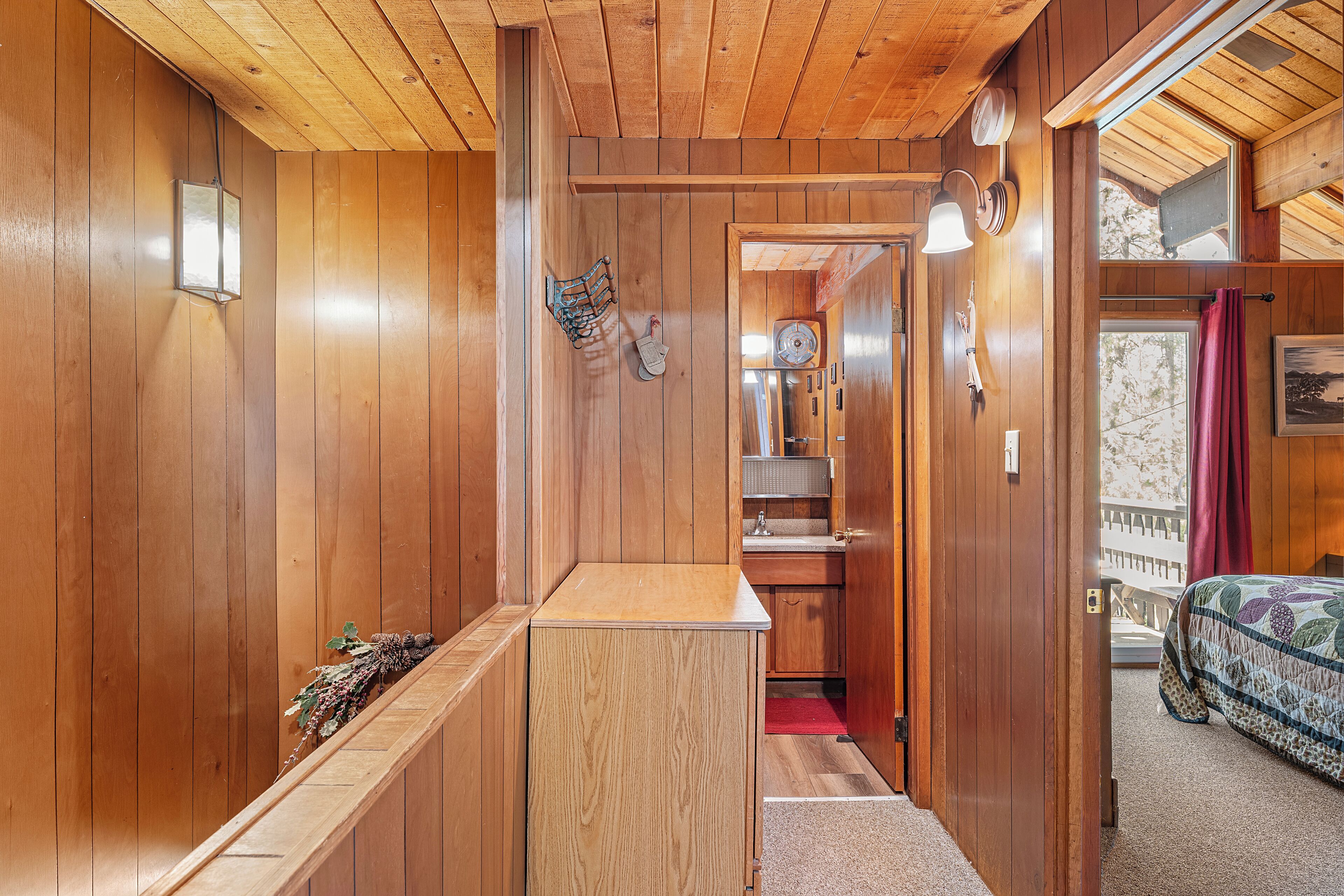 A wooden interior with a narrow hallway leading to a bedroom.