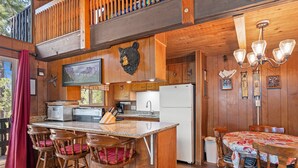 A wooden cabin interior with a kitchen, dining area, and bar seating.