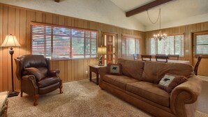 A living room with a leather armchair, a brown sofa, and a wooden floor.