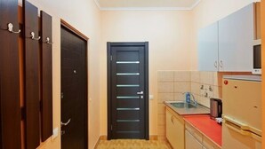 A narrow hallway with a black door, a sink, and cabinets. - 1 Bedroom Apartment on Sq. Staryi Rynok 1 (Lviv)