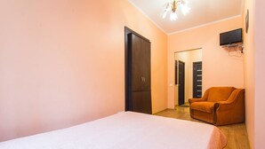 A bedroom with a bed, a wardrobe, a chair, and a television mounted on the wall. - 1 Bedroom Apartment on Sq. Staryi Rynok 1 (Lviv)