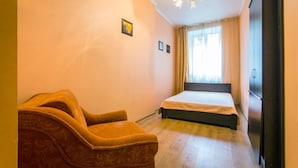 A bedroom with a bed, a chair, a wardrobe, and a window with curtains. - 1 Bedroom Apartment on Sq. Staryi Rynok 1 (Lviv)
