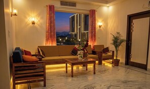 A modern living room with a sofa, chairs, a coffee table, and a potted plant. - Hotel M Villa (Jaipur)