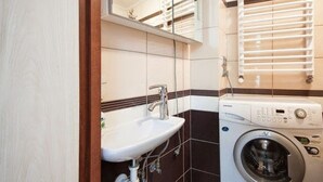 A compact bathroom with a sink, a washing machine, and a mirror. - 1 Bedroom Apartment Knyazya Leva 2 (Lviv)