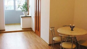 A room with a round table, two chairs, a potted plant, and a window.