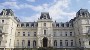 A large, historic building with symmetrical architecture, featuring a central entrance and multiple windows.