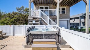 A wooden deck with a hot tub and steps leading to a covered area. - Just For You | 988 ft from the beach | Dog Friendly, Private Pool, Hot Tub | Nags Head (Nags Head)