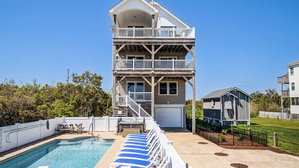 A multi-story building with a pool, outdoor seating, and a staircase leading to the upper levels. - Just For You | 988 ft from the beach | Dog Friendly, Private Pool, Hot Tub | Nags Head (Nags Head)