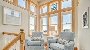 A room with two light blue armchairs, a wooden staircase, and large windows with a view of the city. - Just For You | 988 ft from the beach | Dog Friendly, Private Pool, Hot Tub | Nags Head (Nags Head)