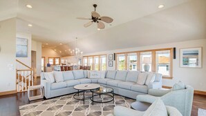 A spacious living room with a large L-shaped sectional sofa, a round coffee table, and a ceiling fan. - Just For You | 988 ft from the beach | Dog Friendly, Private Pool, Hot Tub | Nags Head (Nags Head)