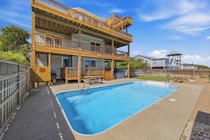 A two-story building with a swimming pool, outdoor seating, and a gazebo.