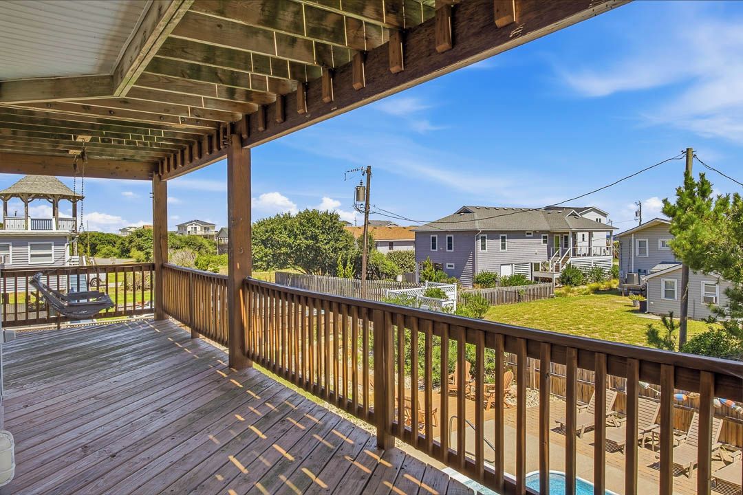 Um deck de madeira com vista para um bairro residencial, incluindo casas e uma piscina.