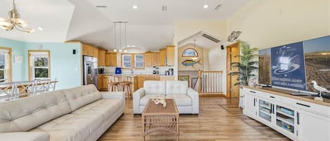A spacious living area with a sofa, a coffee table, and a kitchen in the background.