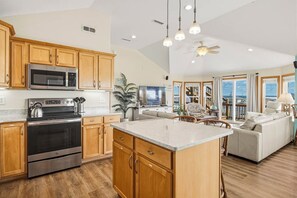 Une cuisine spacieuse avec des meubles en bois, des appareils électroménagers en acier inoxydable et un grand îlot central.